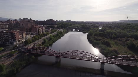 aerial flying over puente reina sofía bridge crossing the calm river tagus