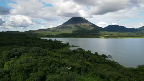 Vista-Aérea-En-Movimiento,-Vista-Panorámica-Del-Lago-Al-Pie-Del-Volcán-Arena-En-Costa-Rica,-Cielo-Azul-Nublado-En-El-Fondo