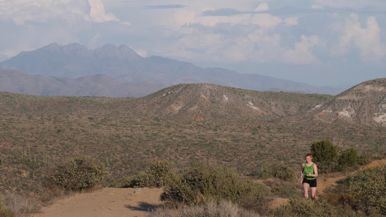 mujer de pelo corto corre por un sendero en el desierto de arizona