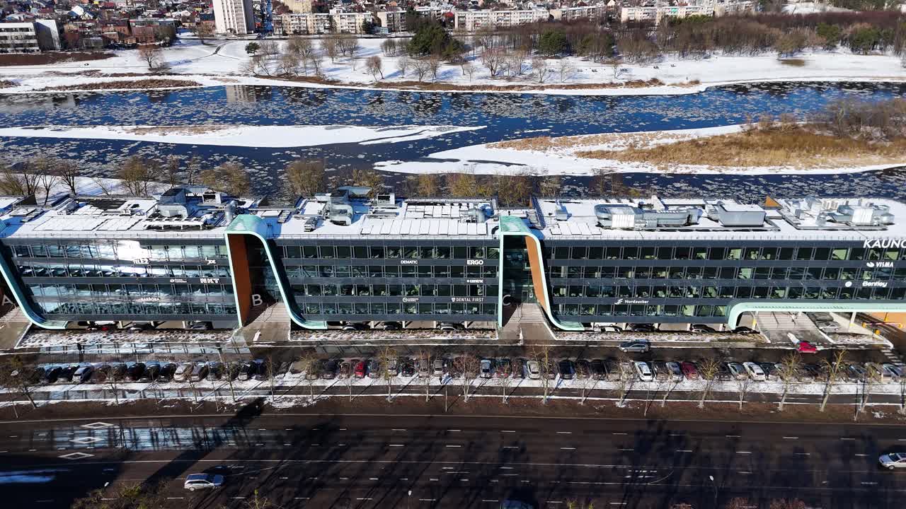 Huge office building near icy river in Kaunas city, aerial view