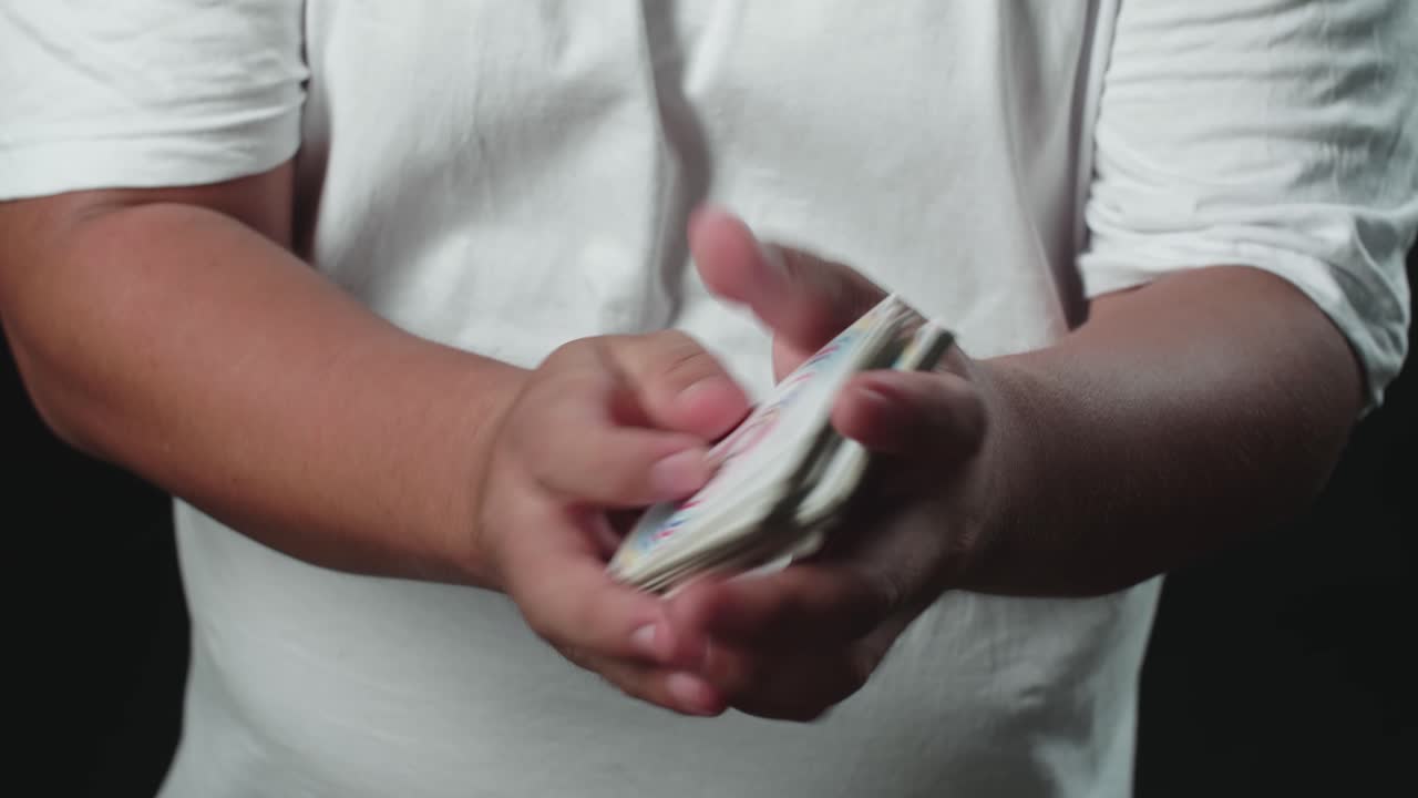 Illusionist begint zijn truc met kaarten te tonen, Cardistry op zwarte achtergrond.