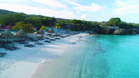 Crystal-clear-blue-ocean-water-and-waves-crash-on-golden-sand-at-sunrise,-Grote-Knip-Curacao