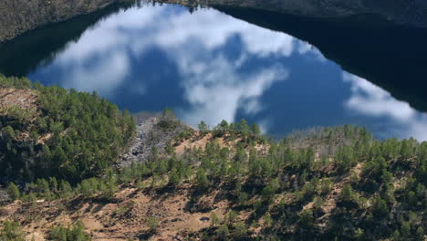 aerial footage capturing a calm alpine lake, perfectly mirroring the mountains and sky above