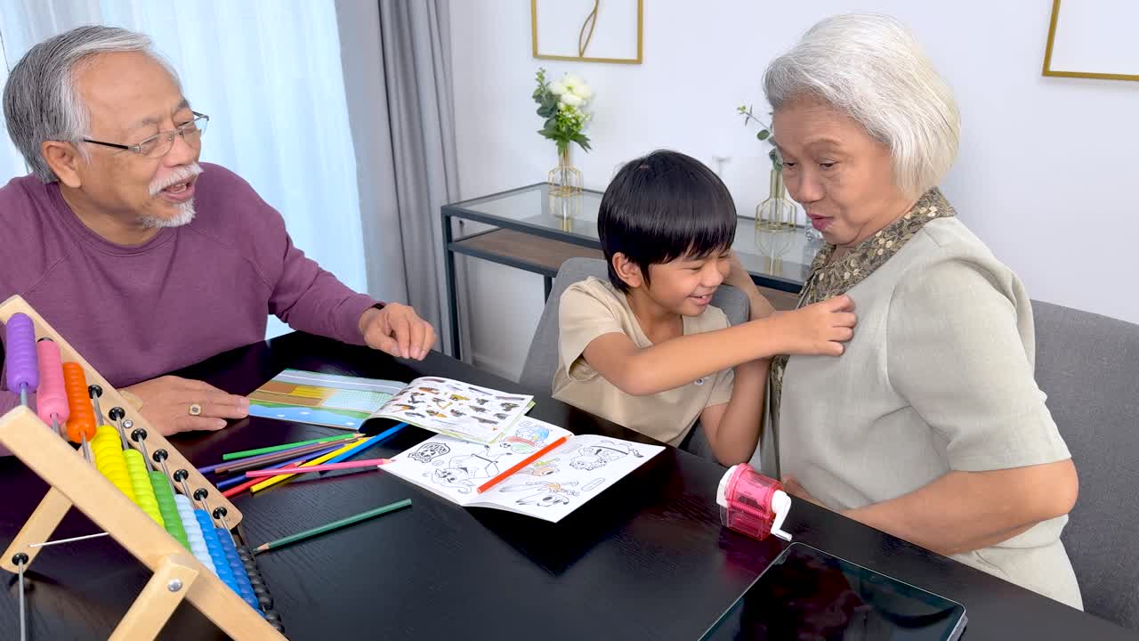 Asian grandparents and child make arts and crafts together in a cheerful, sunlit home
