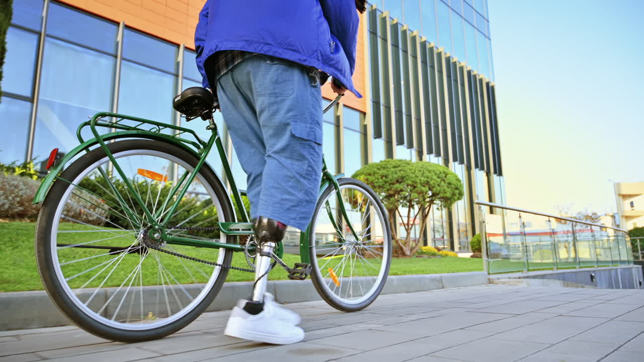 View of a man with prosthetic legs. Walking with a bicycle on the street