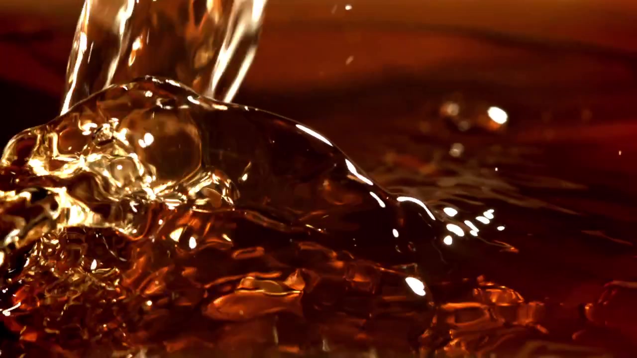 Liquido ambrato che si versa e schizza al rallentatore
