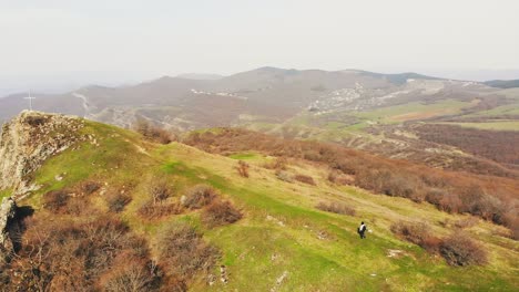 aerial panning view woman backpacker hikes in nature towards cross up hill. life destinations, life and religion concept