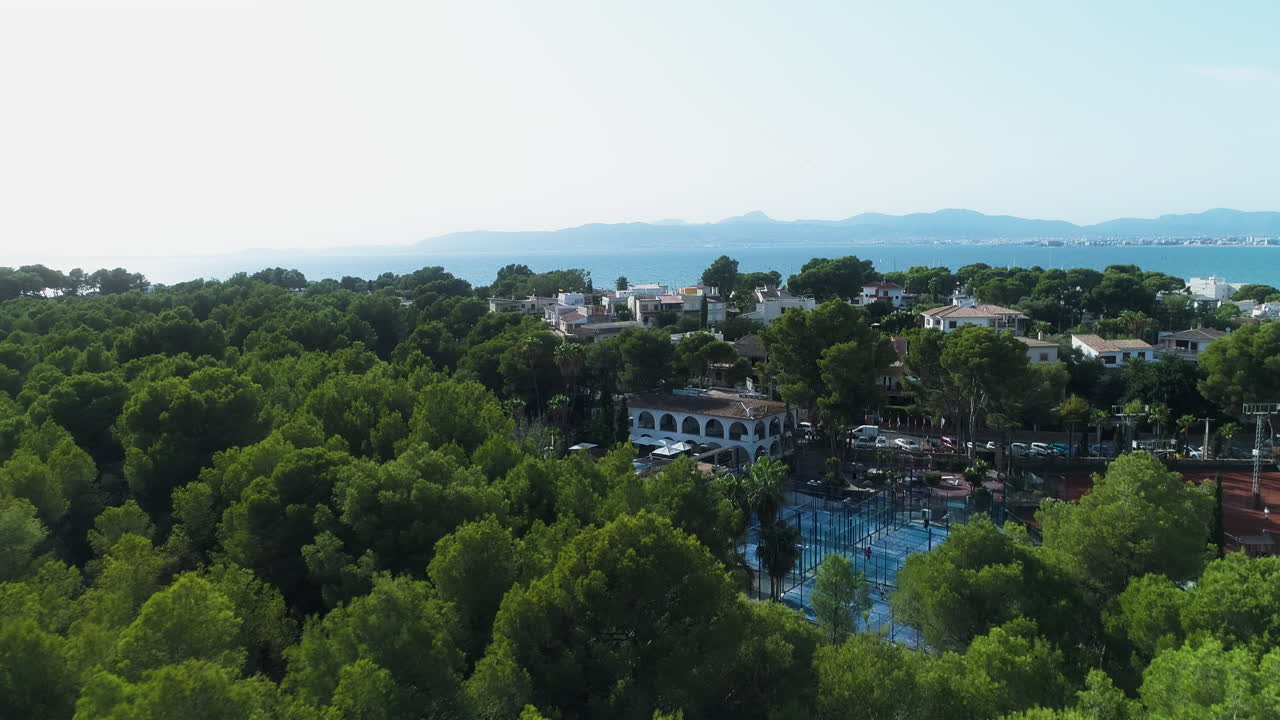Il drone si allontana dai campi da tennis di una villa verso le montagne.
