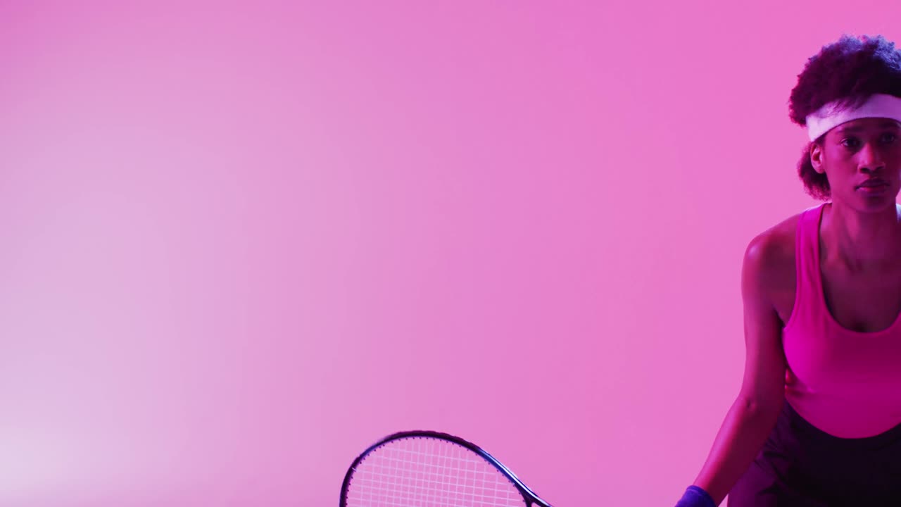 초점을 맞춘 아프리카계 미국인 여성 테니스 선수가 네온 분홍색 번개에 공을 때리는 비디오