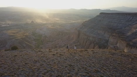 slo mo sunrise aerial of hikers on mesa above eroded fairy chimneys