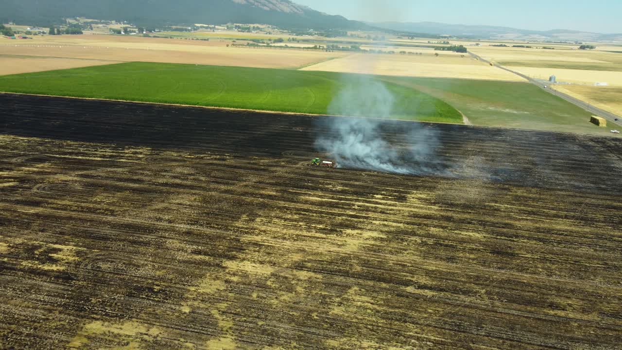US, Oregon, La Grande, 2025-08-11 - Drone view of a tractor pulling a large weed burner setting the dry plants on fire