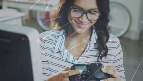 Animation-of-dna-rotating-over-caucasian-woman-working-with-camera-in-office