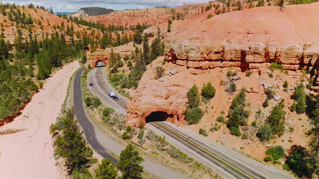 Stunning scenery of bright canyons on sunny day. Amazing rocks of Arches Canyons with green pine trees and roads going through the park.