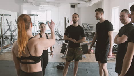 mujer joven y fuerte choca los cinco con sus alumnos en el gimnasio