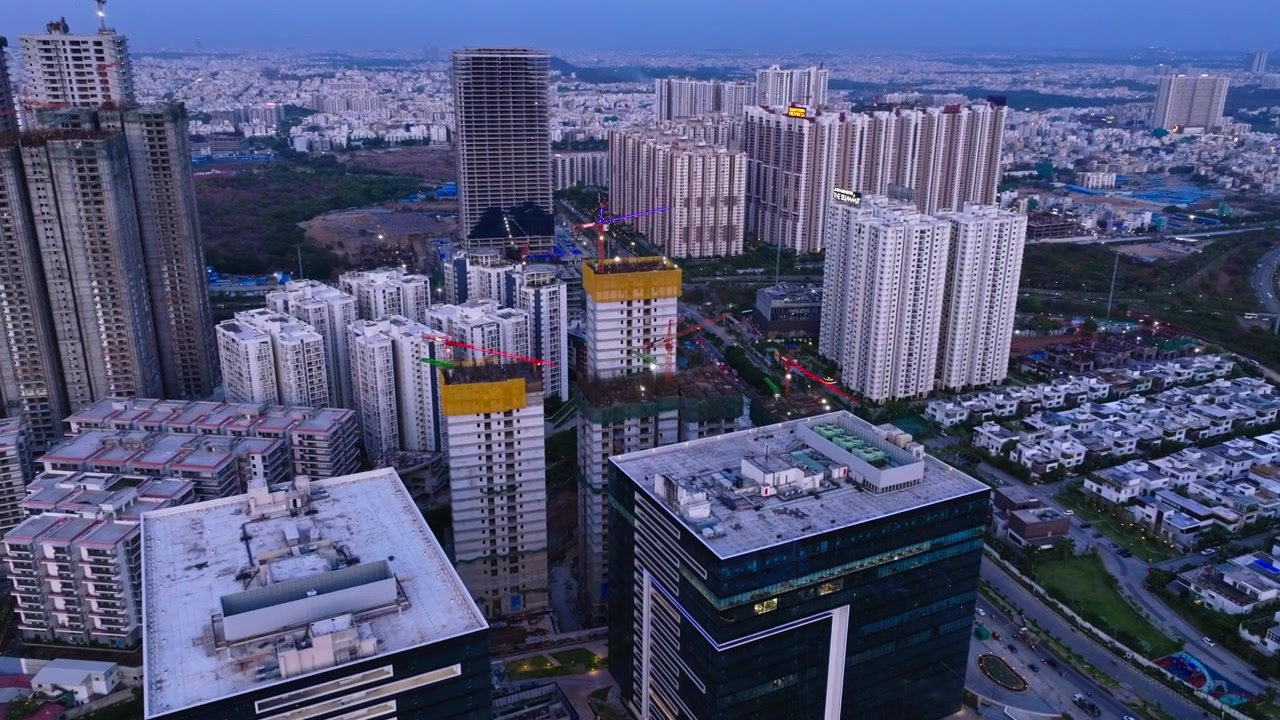 Edifícios comerciais com fachada de vidro, com arranha-céus em construção ativa, vilas de luxo e complexo de condomínios em Narsingi, Hyderabad, Telangana, Índia. Durante o dia, tomada de aproximação, tomada de drone, 4K.