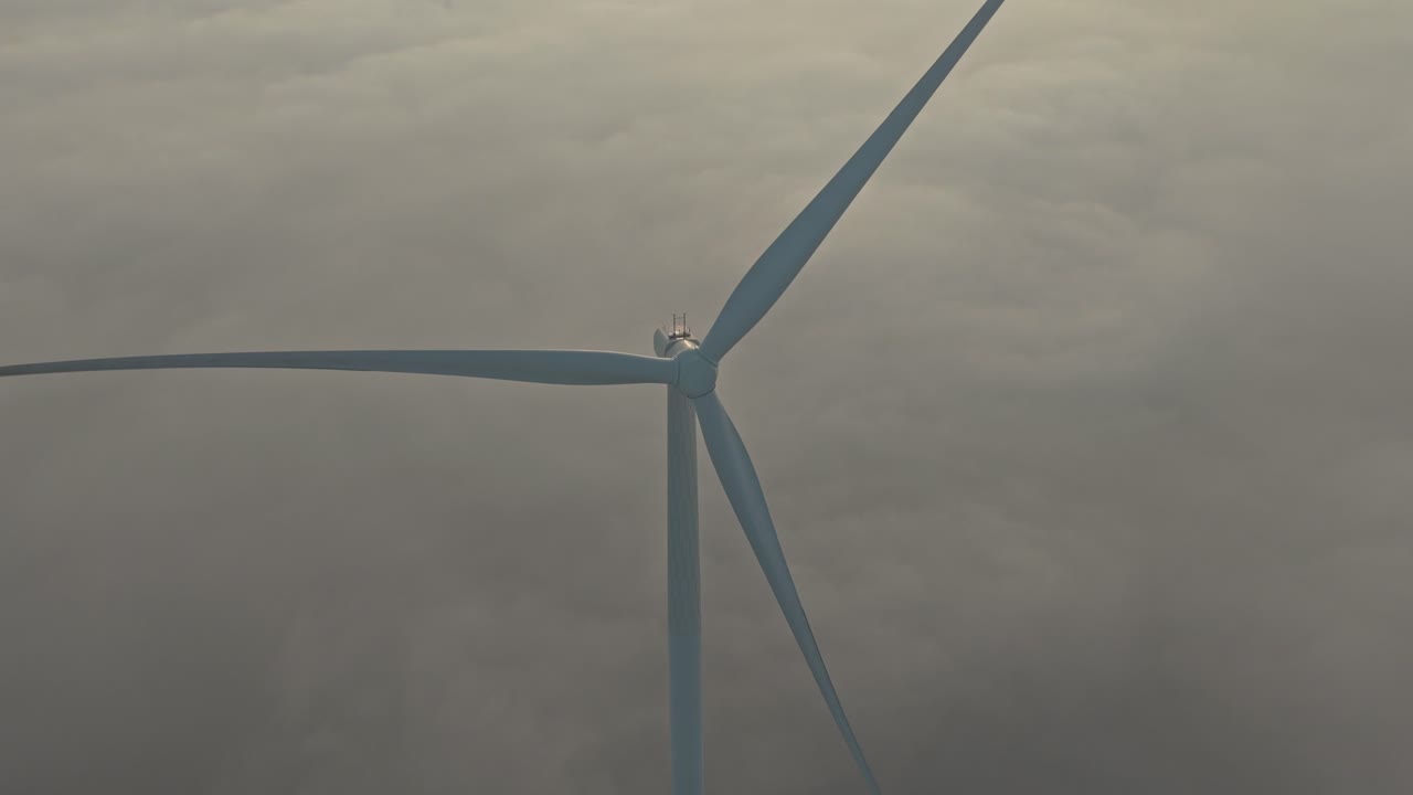 Vista aerea di turbine eoliche che girano sopra nuvole nebbiose