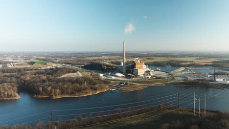 electrical power plant chimney emitting smoke on shore of lake flint creek in arkansas, usa