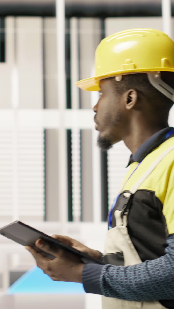Vertical video Serviceman holding tablet walking in factory, inspecting systems