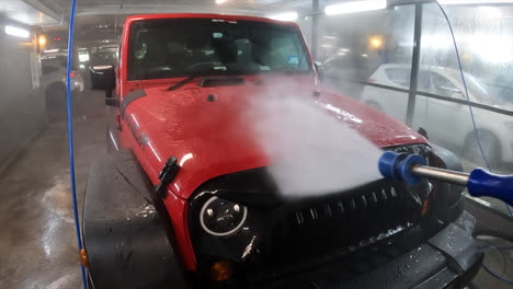 pov power washing the front of a red 4wd vehicle