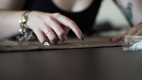 Hands-of-woman-adding-hangers-to-freshly-sewed-curtain,-front-view