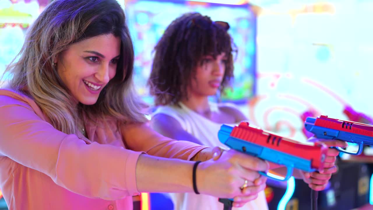 Two women playing a shooting game in an arcade
