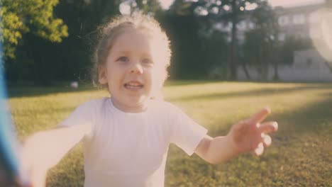 blonde girl plays with butterfly net in green sunny garden