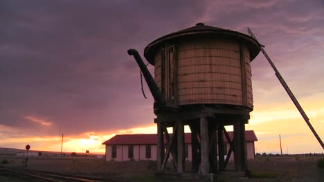 una torre de agua a lo largo de una vía férrea abandonada al atardecer