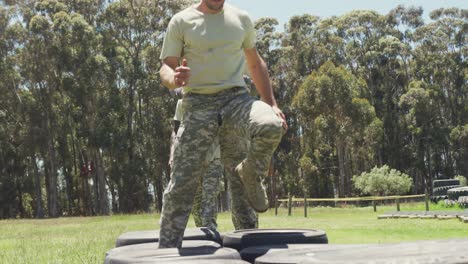 grupo diverso de soldados corriendo a través de neumáticos de automóviles en el curso de obstáculos del ejército