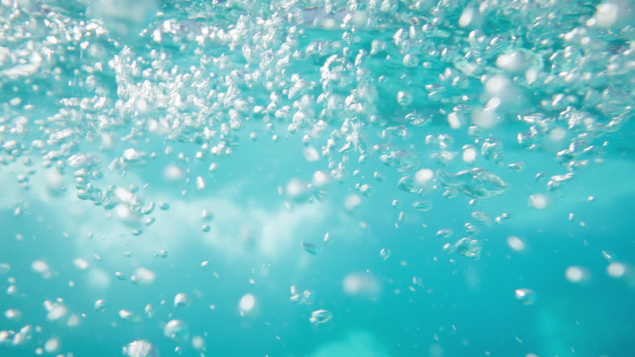 Underwater view of moving water with air bubbles turbulence and light reflections. Dynamic motion and fluid textures create an abstract and immersive aquatic atmosphere