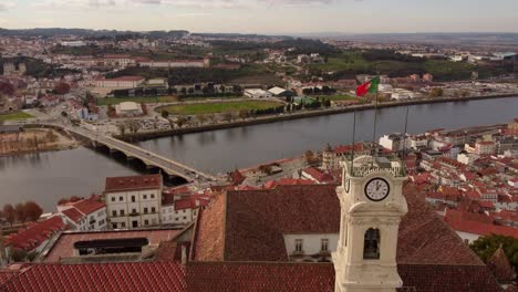 aerial zoom in university's clock tower in coimbra cityscape drone view of the river and the bridge with portugal flag