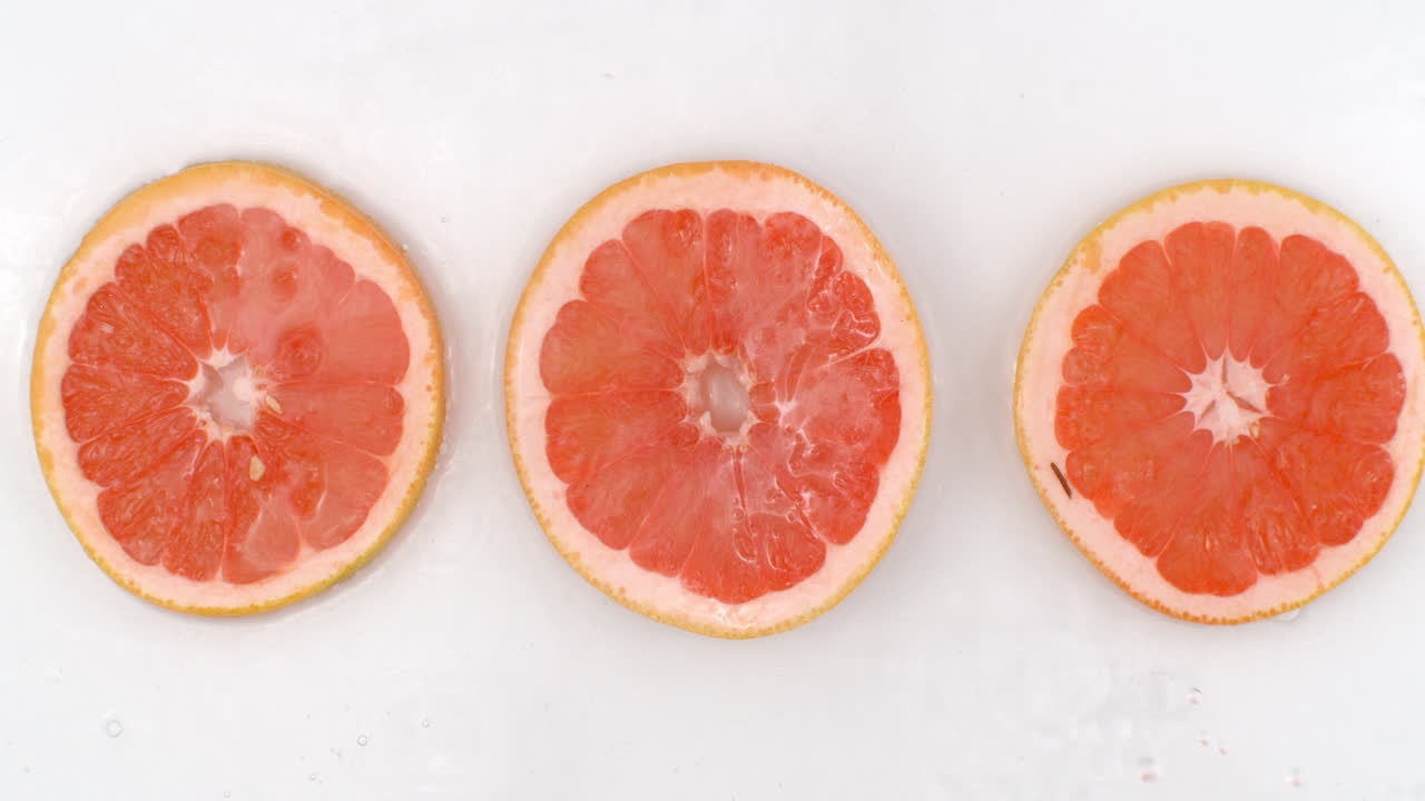 Super Slow Motion Shot of Splashing Water to grapefruit Slices view from above