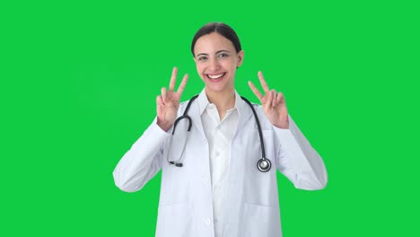 Happy-Indian-female-doctor-showing-victory-sign-Green-screen