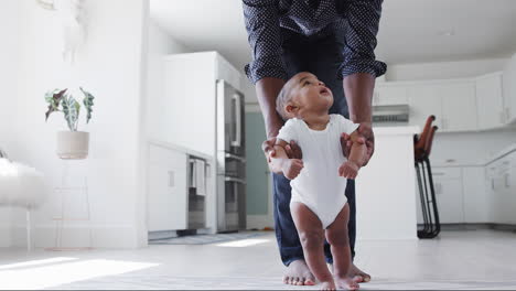 Close-Up-Of-Father-Encouraging-Smiling-Baby-Son-To-Take-First-Steps-And-Walk-At-Home