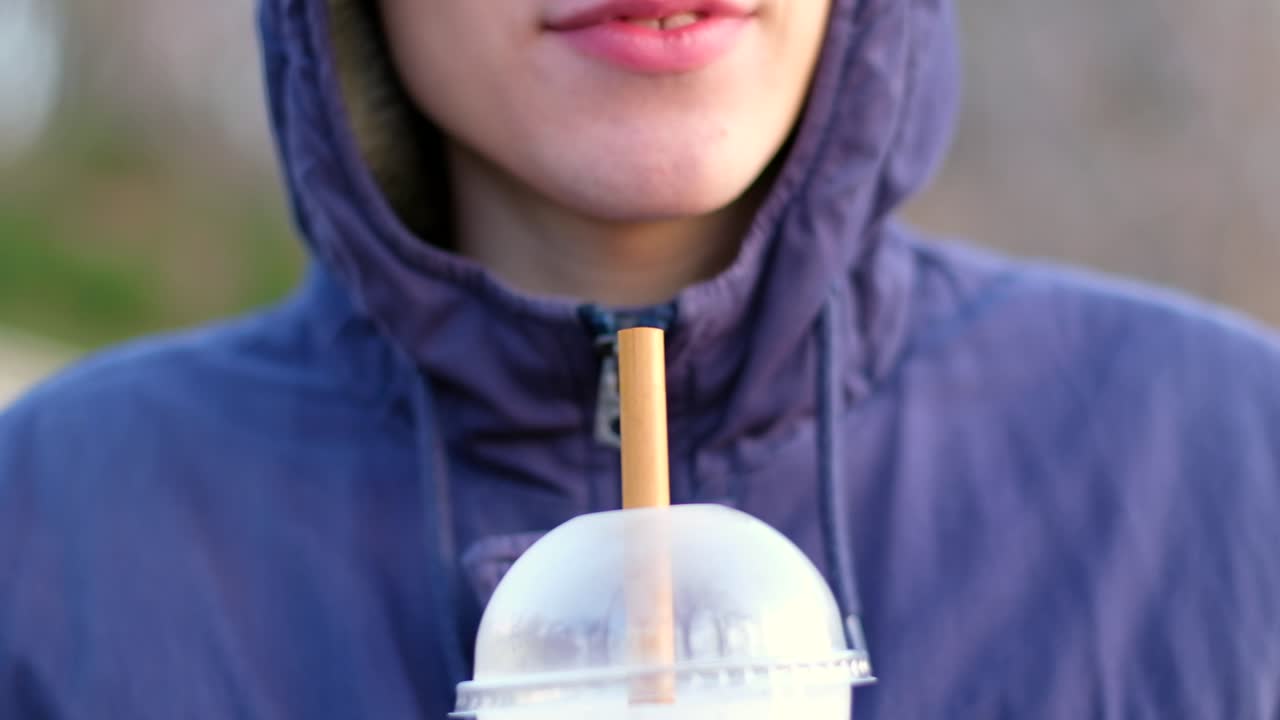 Young man smiling and drink from a bamboo straw ice coffee