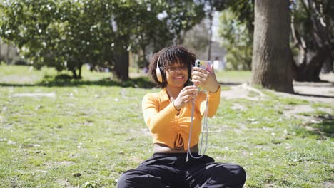 Mujer-Negra-Feliz-Con-Auriculares-Tomando-Selfie-En-El-Césped