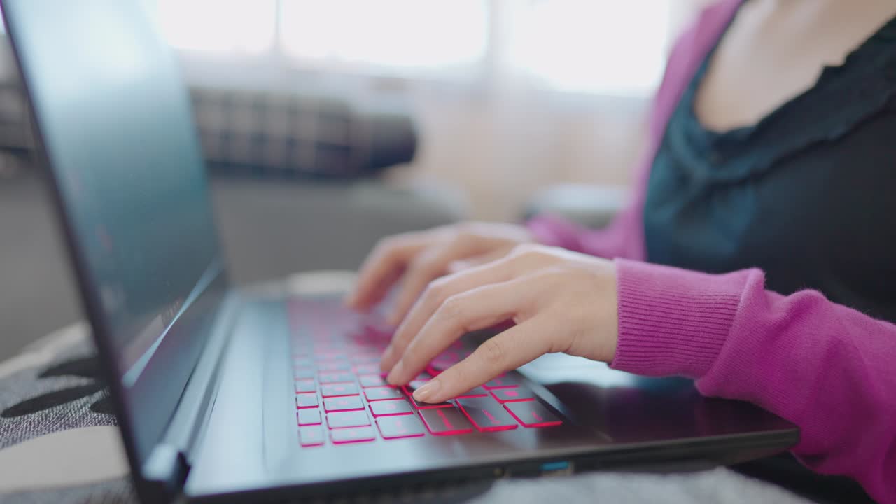 una mujer en primer plano sentada en un sofá escribiendo información en una computadora portátil para comprar en línea en casa