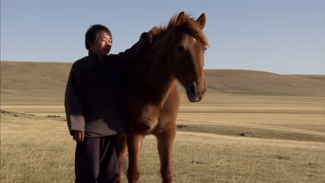 man and horse in a vast grassy landscape