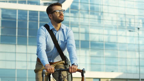 Cámara-Rodando-Alrededor-De-Un-Apuesto-Joven-Con-Gafas-Y-Estilo-Informal-Sentado-En-La-Bicicleta-Y-Pensando