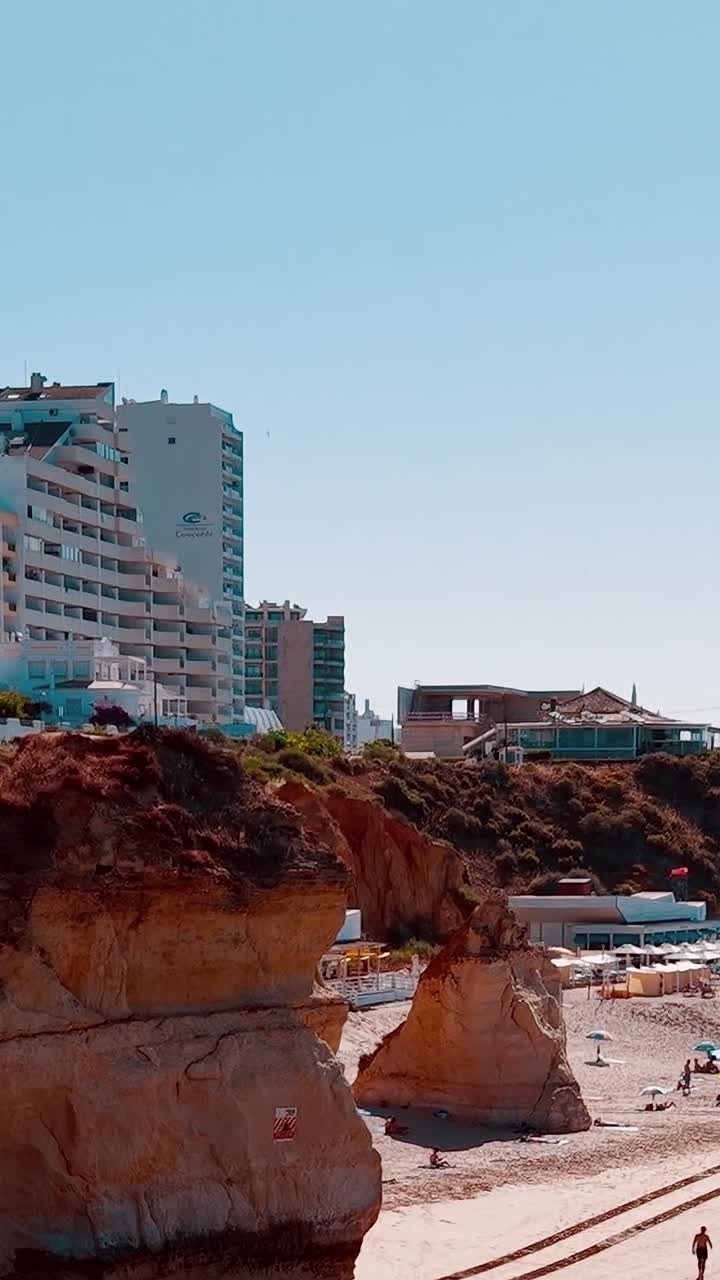 Visitatori che passeggiano sulla spiaggia in Portogallo vicino a edifici alti durante il giorno