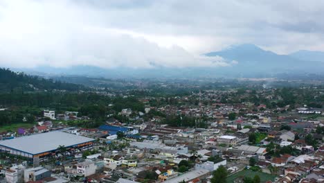 Mountains-and-Bandung-residential-skyline-on-a-cloudy-day-in-Indonesia,-aerial