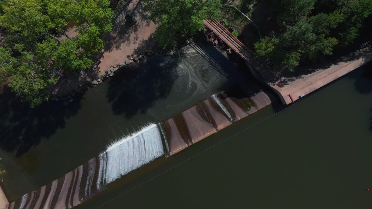 Evergreen Lake House waterfall dam Park and Rec Center Golf Course Keys on the green downtown mountain town summer sunny blue sky flag water dam Colorado aerial drone upward slowly motion