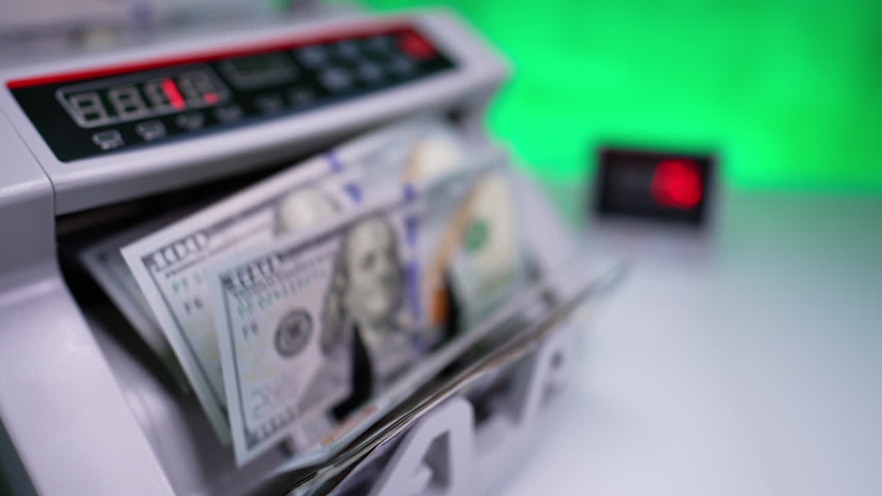 Cash counting machine is switched on. American one hundred dollars are rotated in bank equipment. Close up. Blurred backdrop.