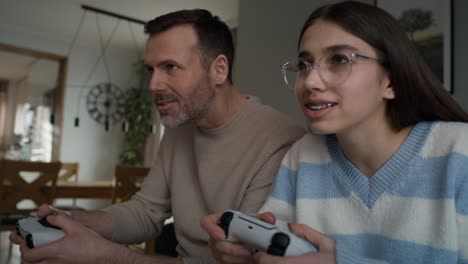 caucasian teenager girl and her father playing at video game with game controller