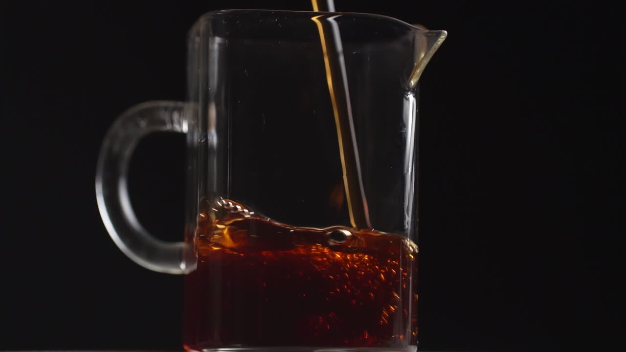 vertiendo té en una jarra de vidrio