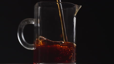 pouring tea into a glass pitcher