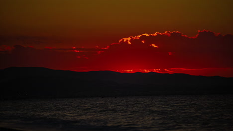 timelapse of a golden sunrise at the beach with mountains in background