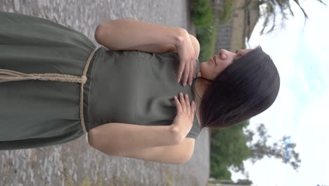 Hermosa-Mujer-Hispana-De-Pelo-Largo-Latino-Posando-Con-Vestido-Verde,-Vertical-Al-Aire-Libre