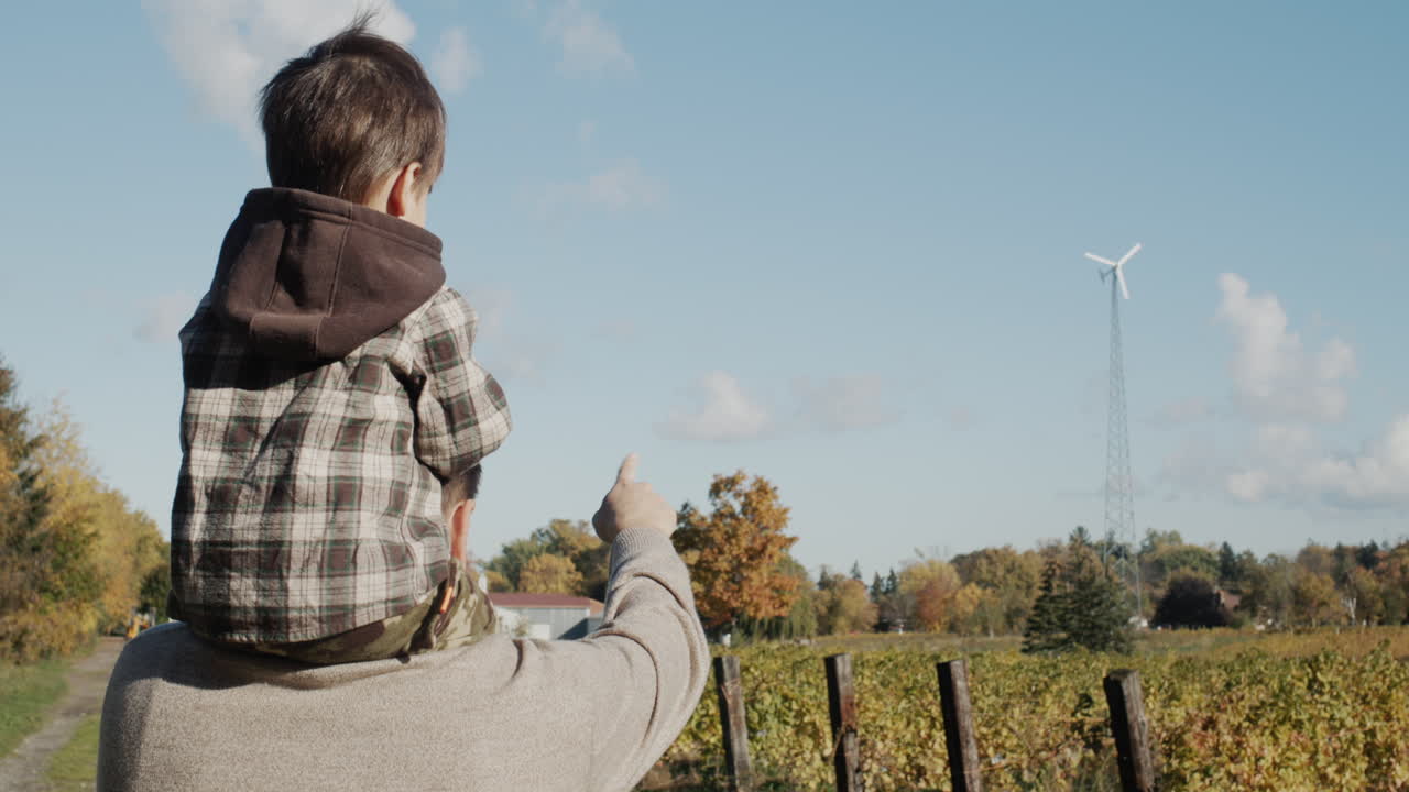 농부 아버지는 어린 아들에게 농장에 설치된 풍력 터빈을 보여줍니다.
