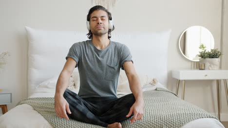 man meditating in bedroom with headphones