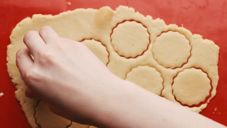 close up woman hand making cookies in the round shape on the red silicone baking mat.